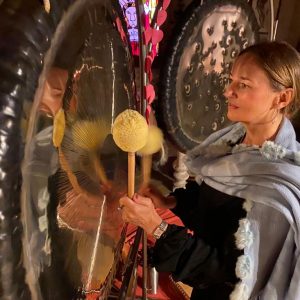 Heike Ott steht mit einem Schlegel vor zwei großen Gongs
